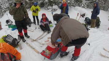 person preparing food from a red sled in the snow