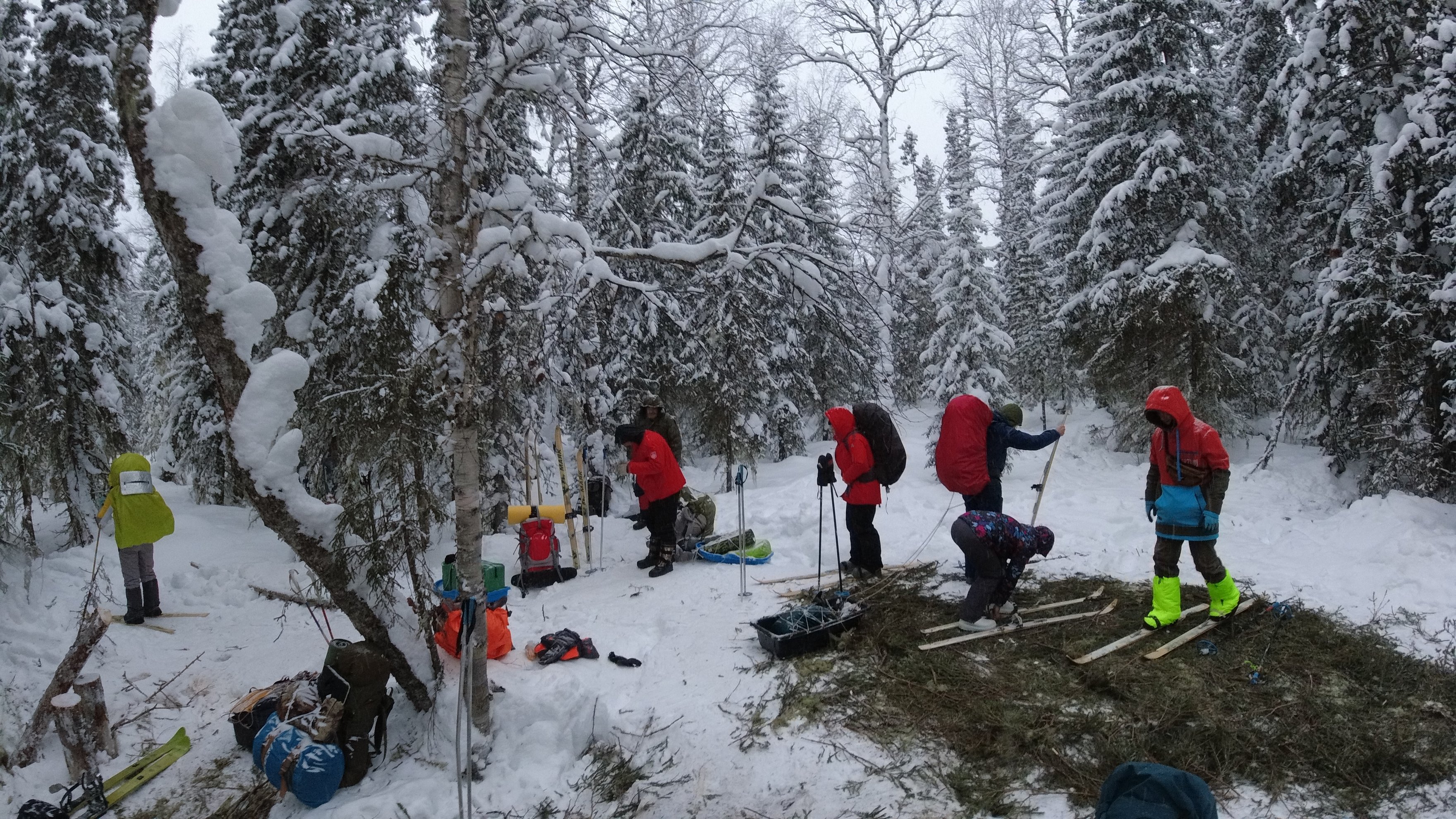 group preparing the ground and fireplace in a snowy forest