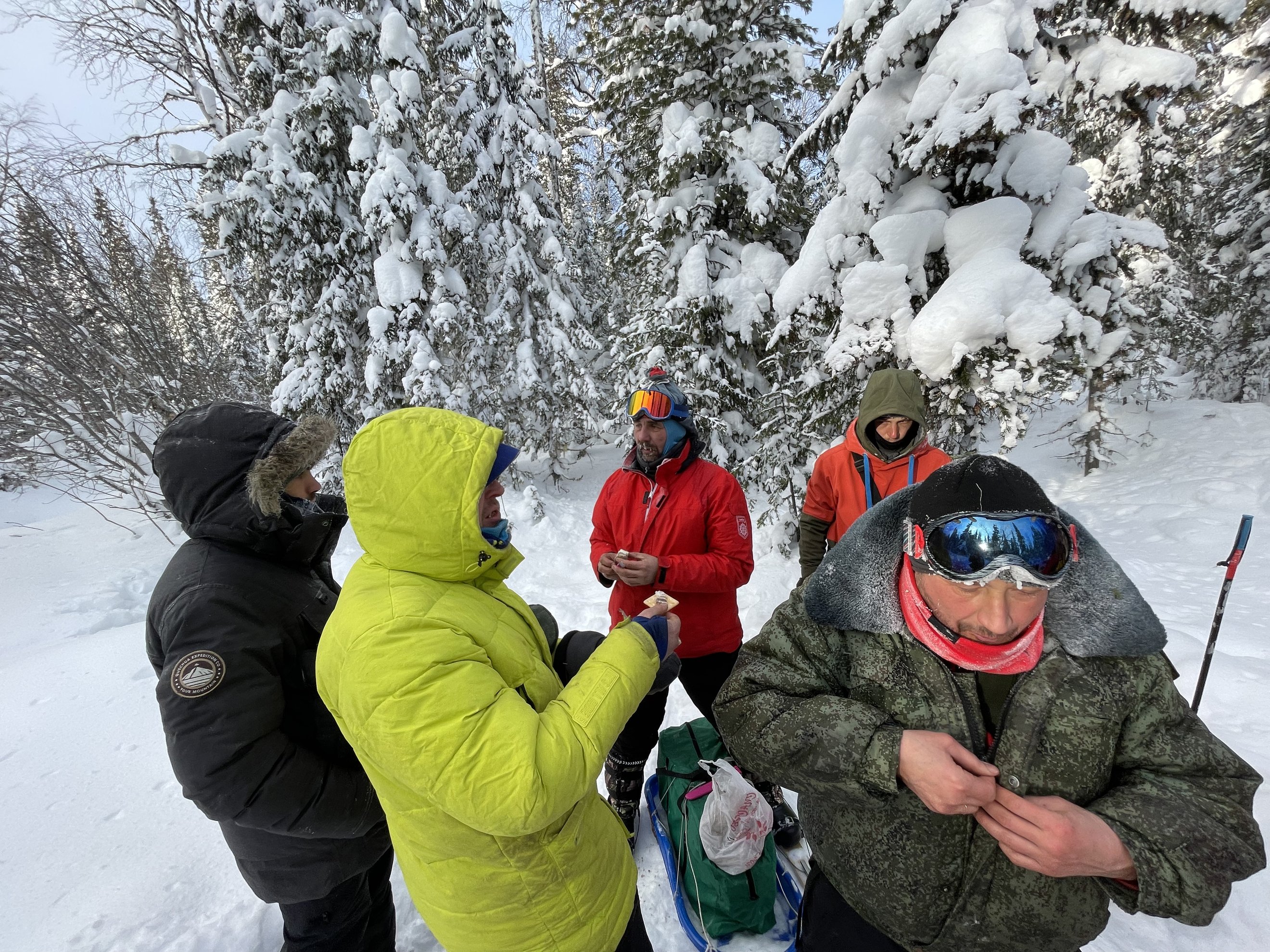 grupo de pessoas com equipamento de inverno a comer durante uma pausa