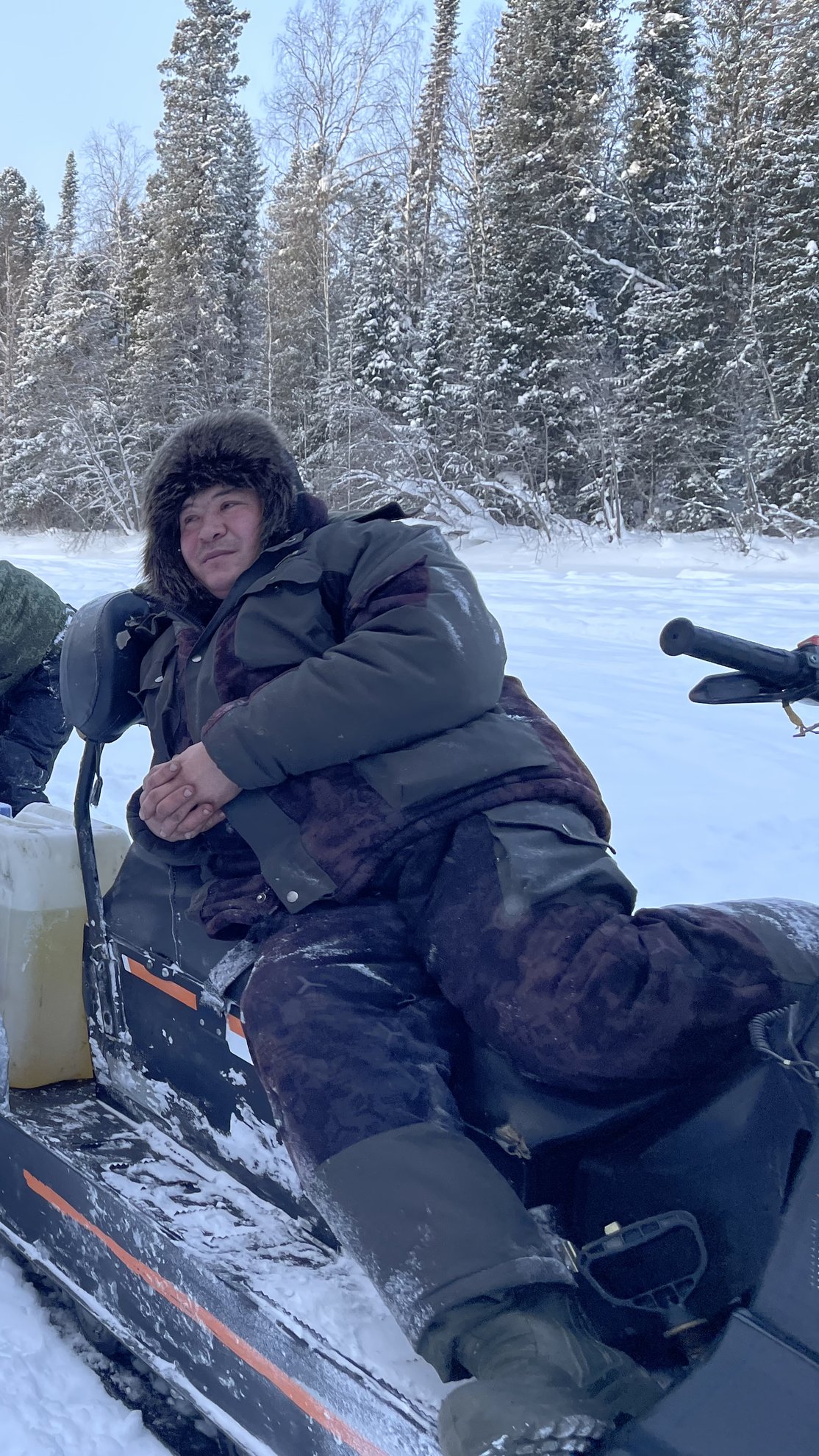 Mansi snowmobile driver resting on a snowmobile