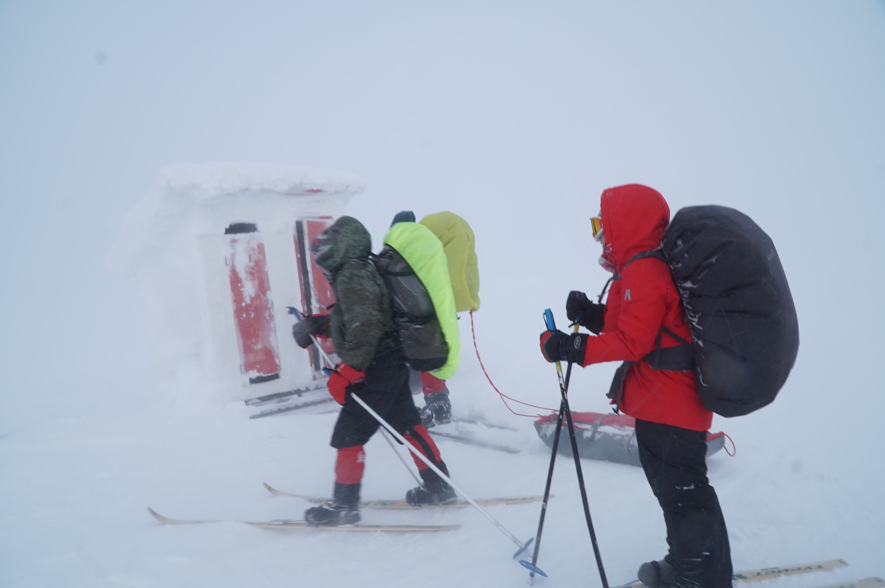 Skiers with backpacks standing near a snow-covered mountain module