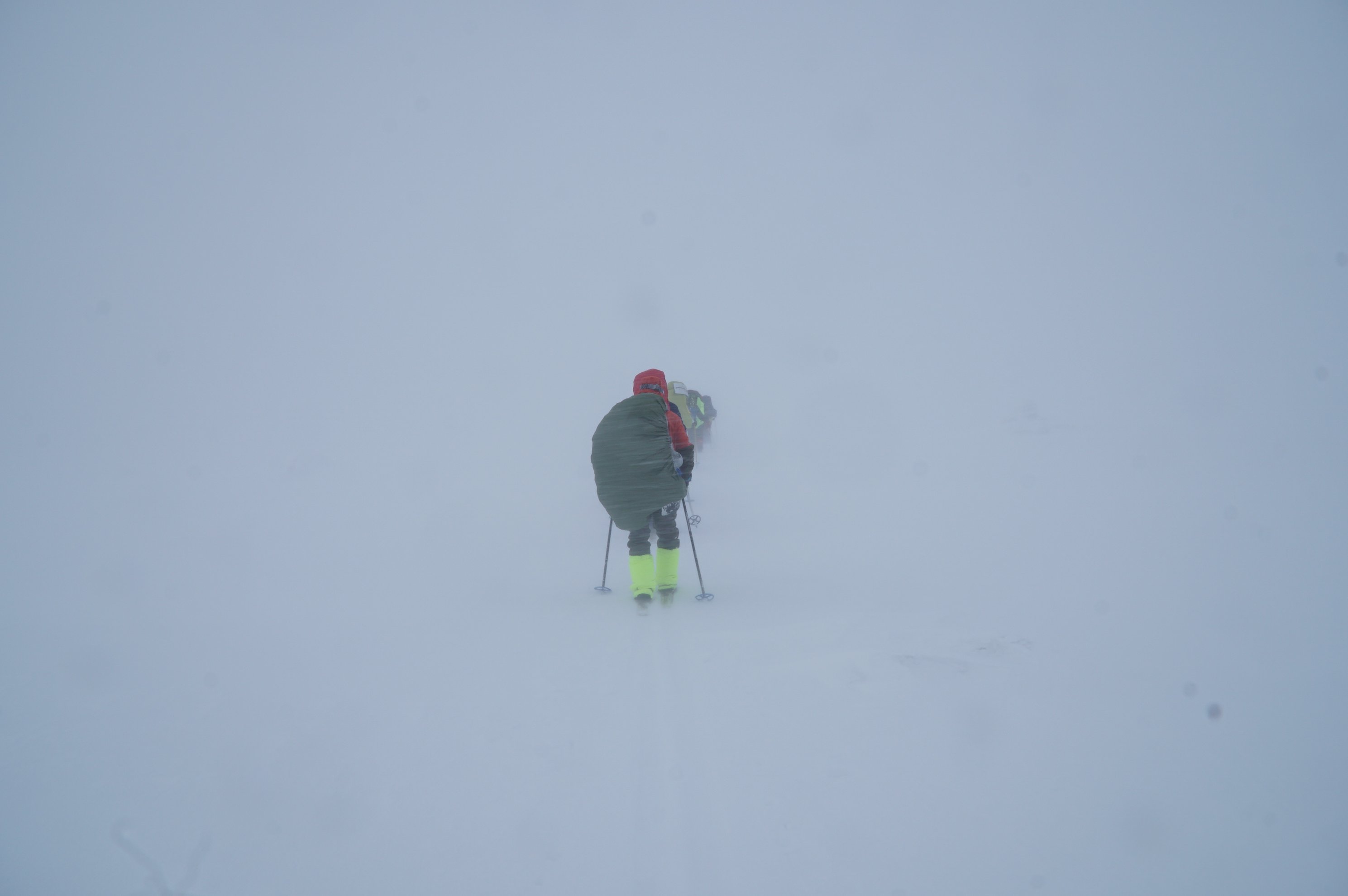 Person skiing through heavy snow and fog from behind