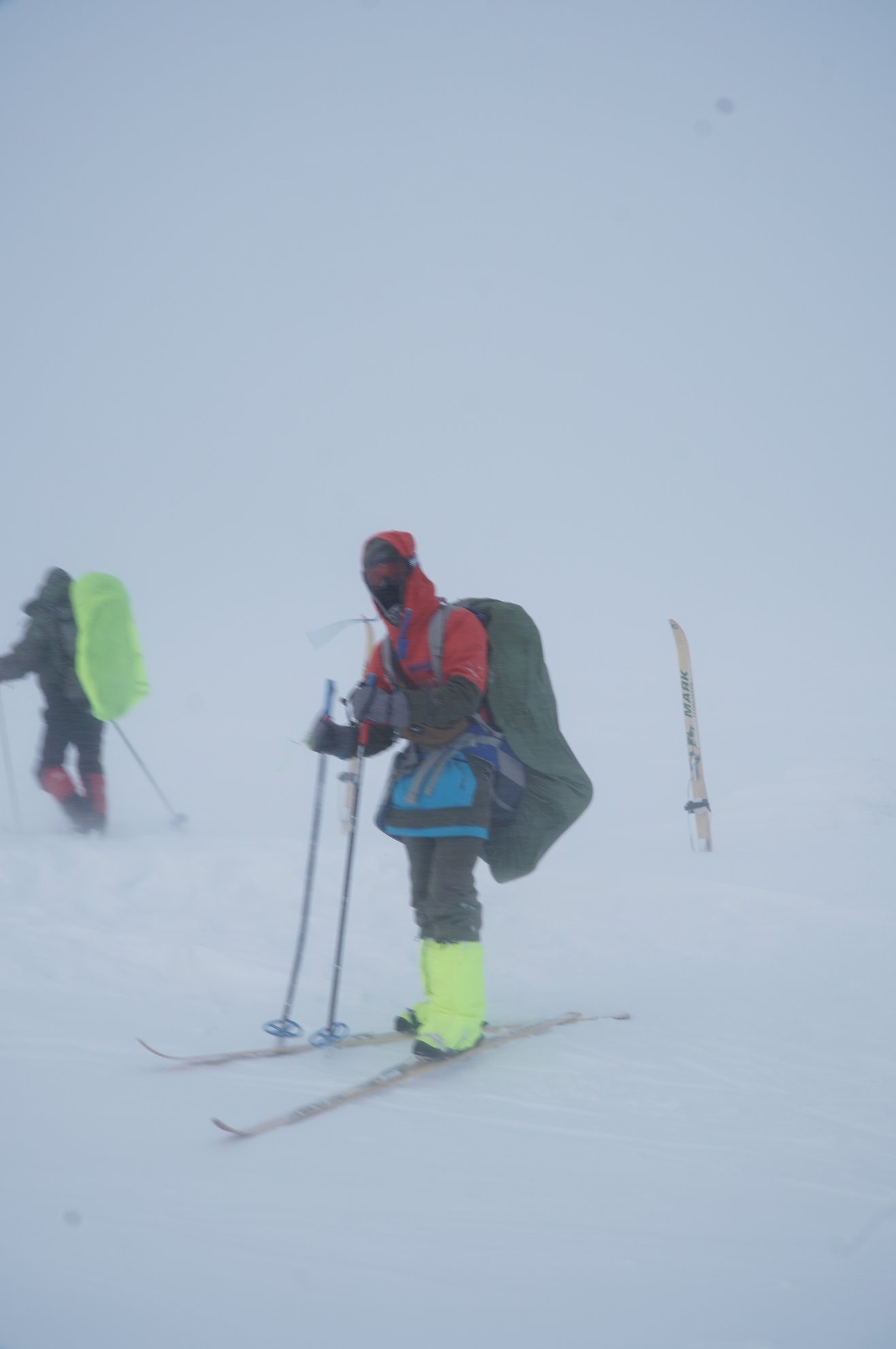 Person in red jacket skiing through a whiteout
