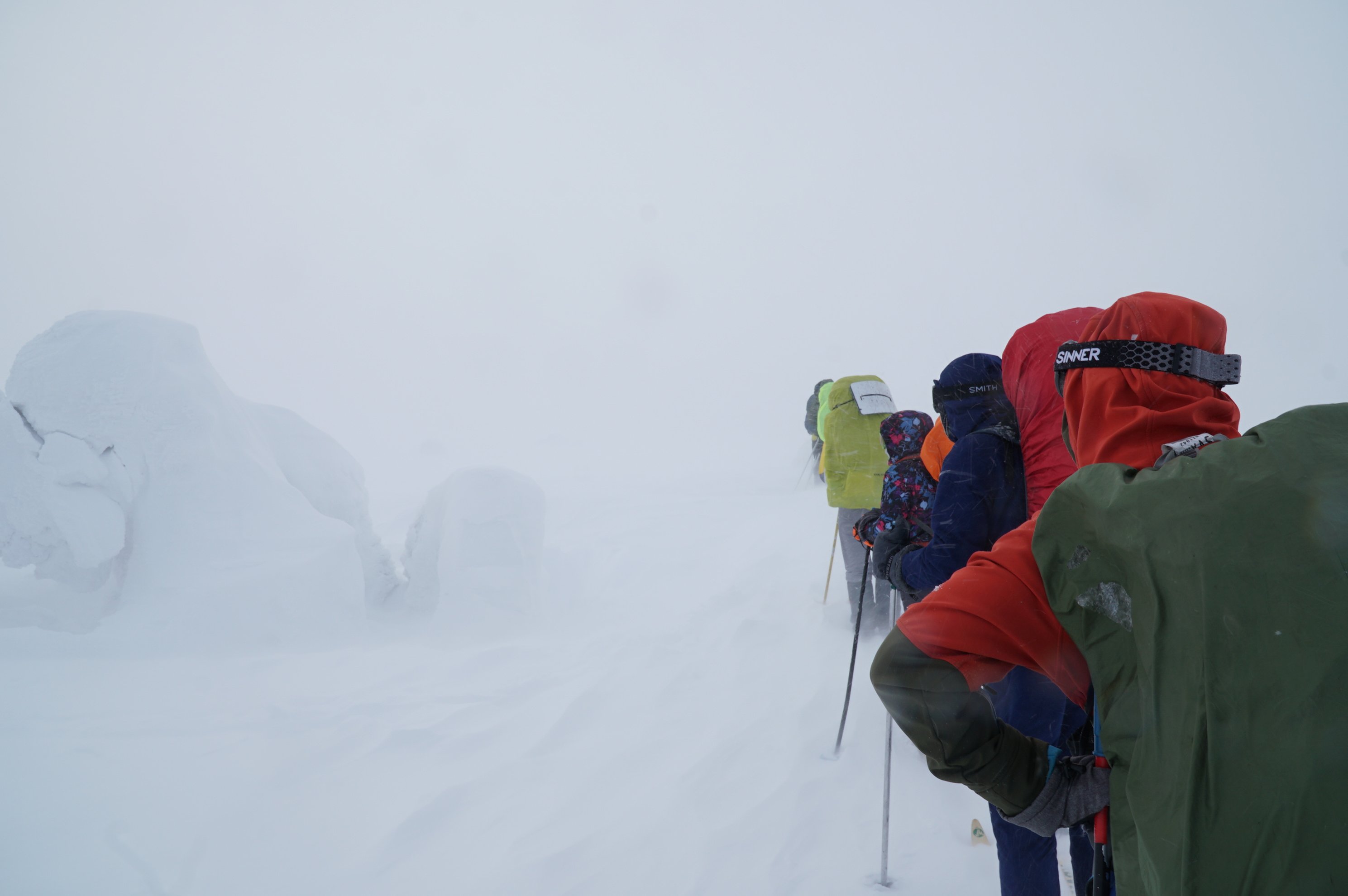 group of skiers moving through deep snow in fog