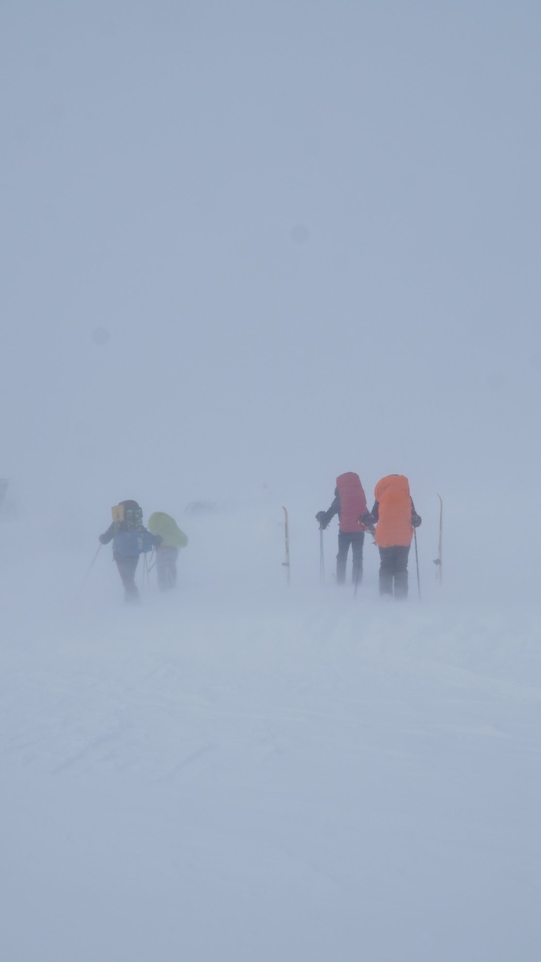 people skiing through thick fog and snow