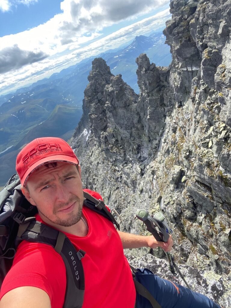 man in red hat with hiking gear on rocky slope