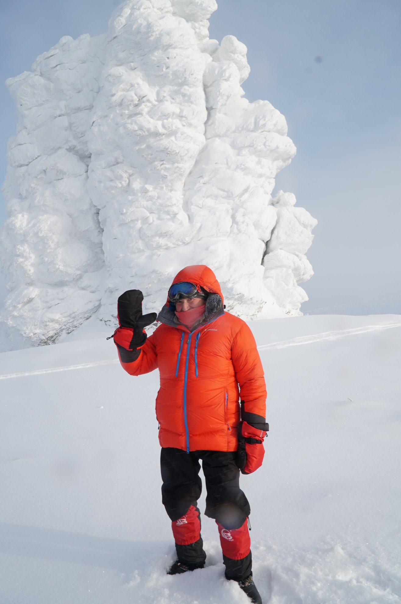 pessoa com equipamento de inverno cor de laranja junto a uma formação rochosa coberta de neve