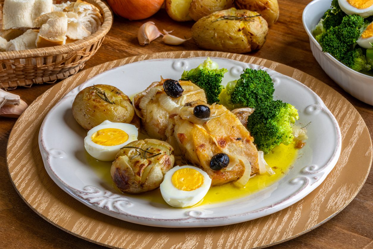 Top-down view of plated cod with sides and bread basket.