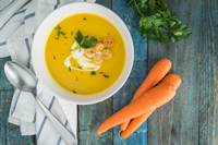 top down view of soup bowl next to raw carrots