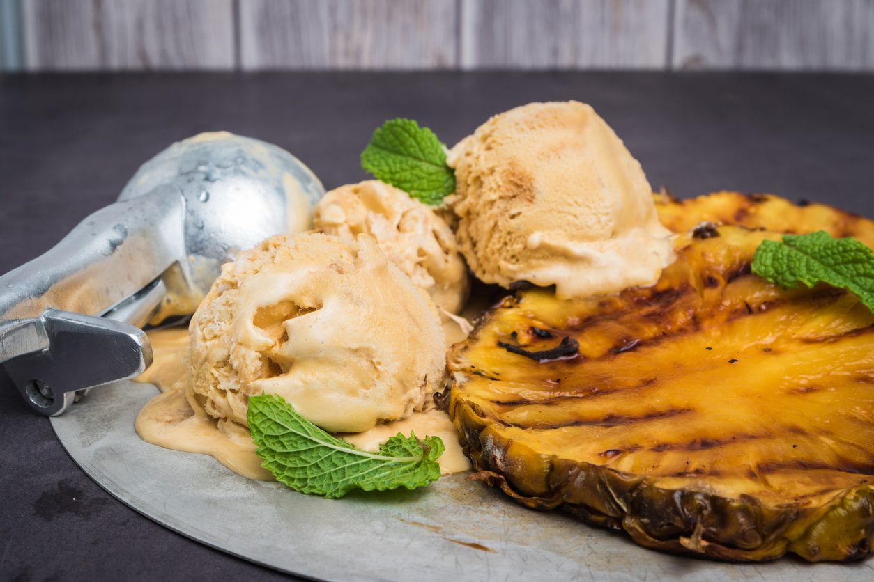Close-up of grilled pineapple slices with ice cream and scoop