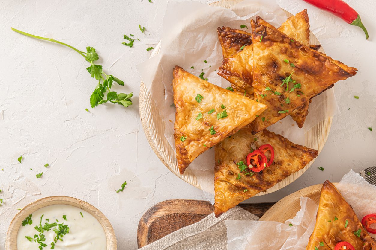 Top down view of samosas on wooden plates with dip