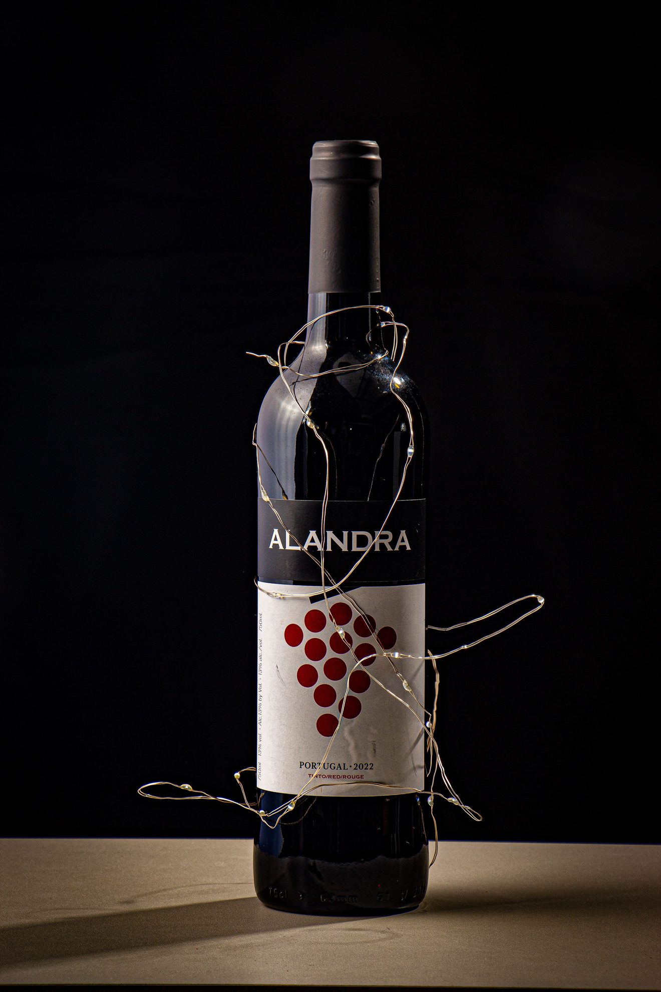 bottle wrapped in fairy lights against black background