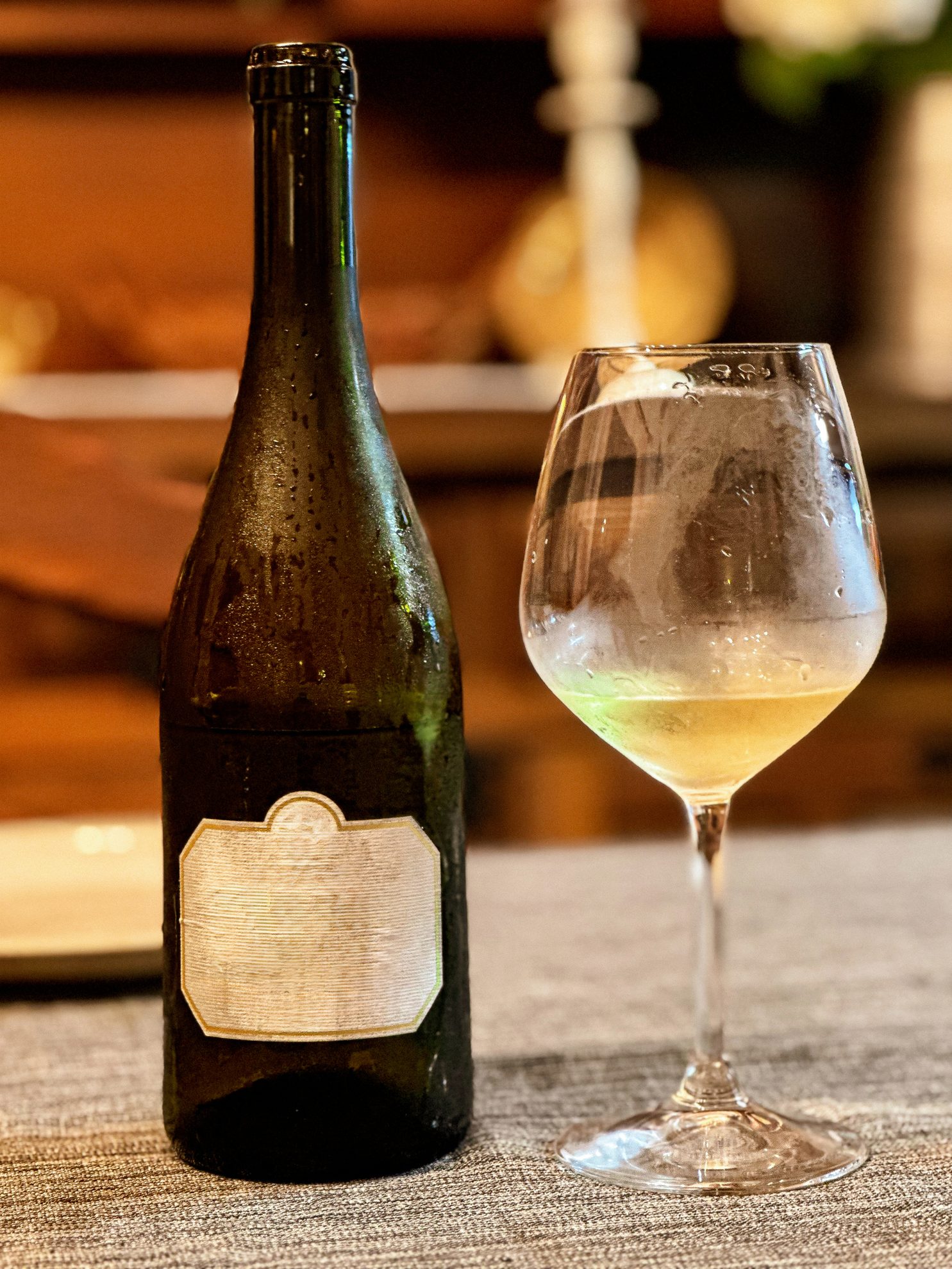 Chilled bottle and glass of white wine on a table