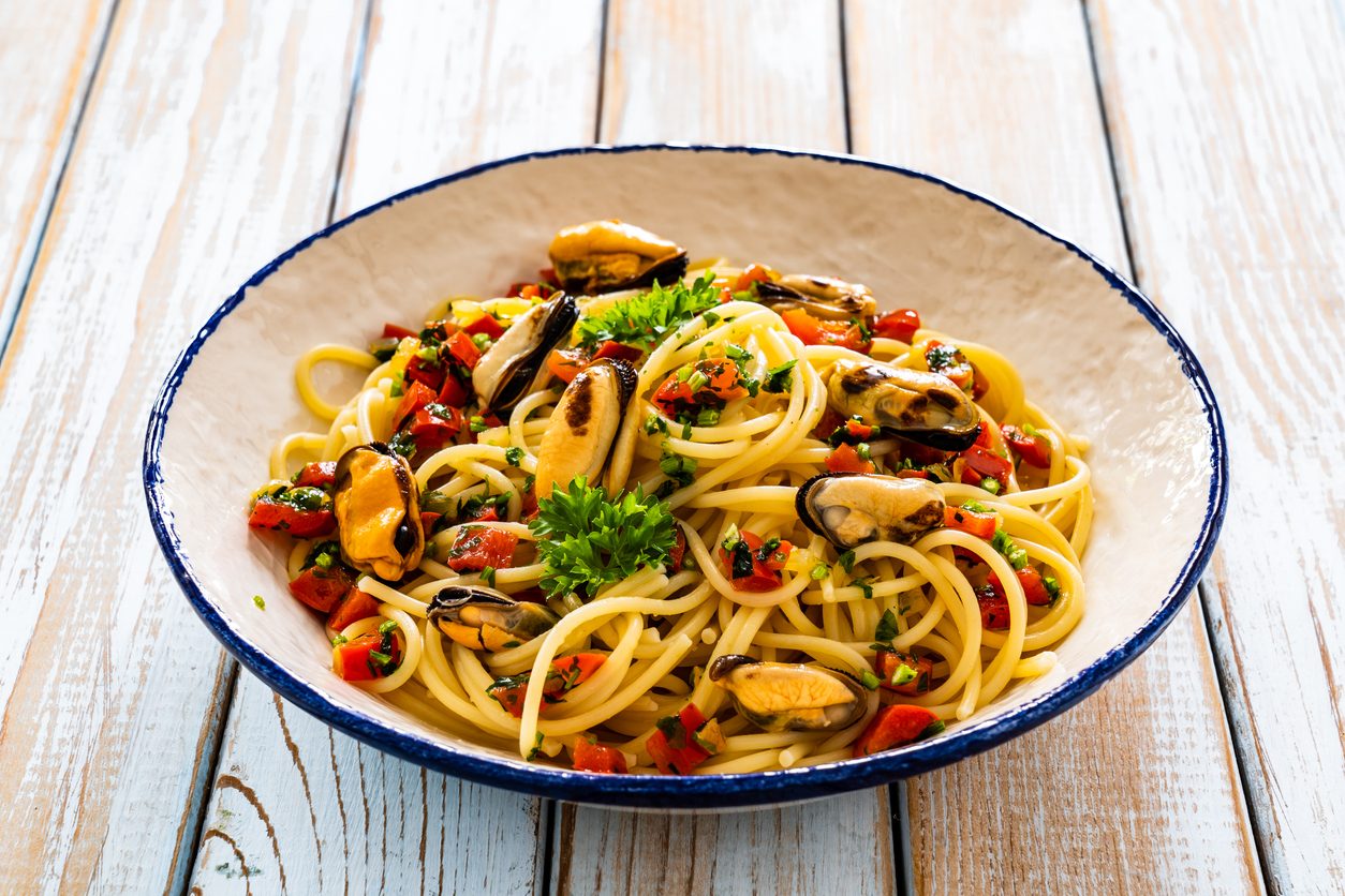 Top-down view of pasta in a white bowl with blue rim