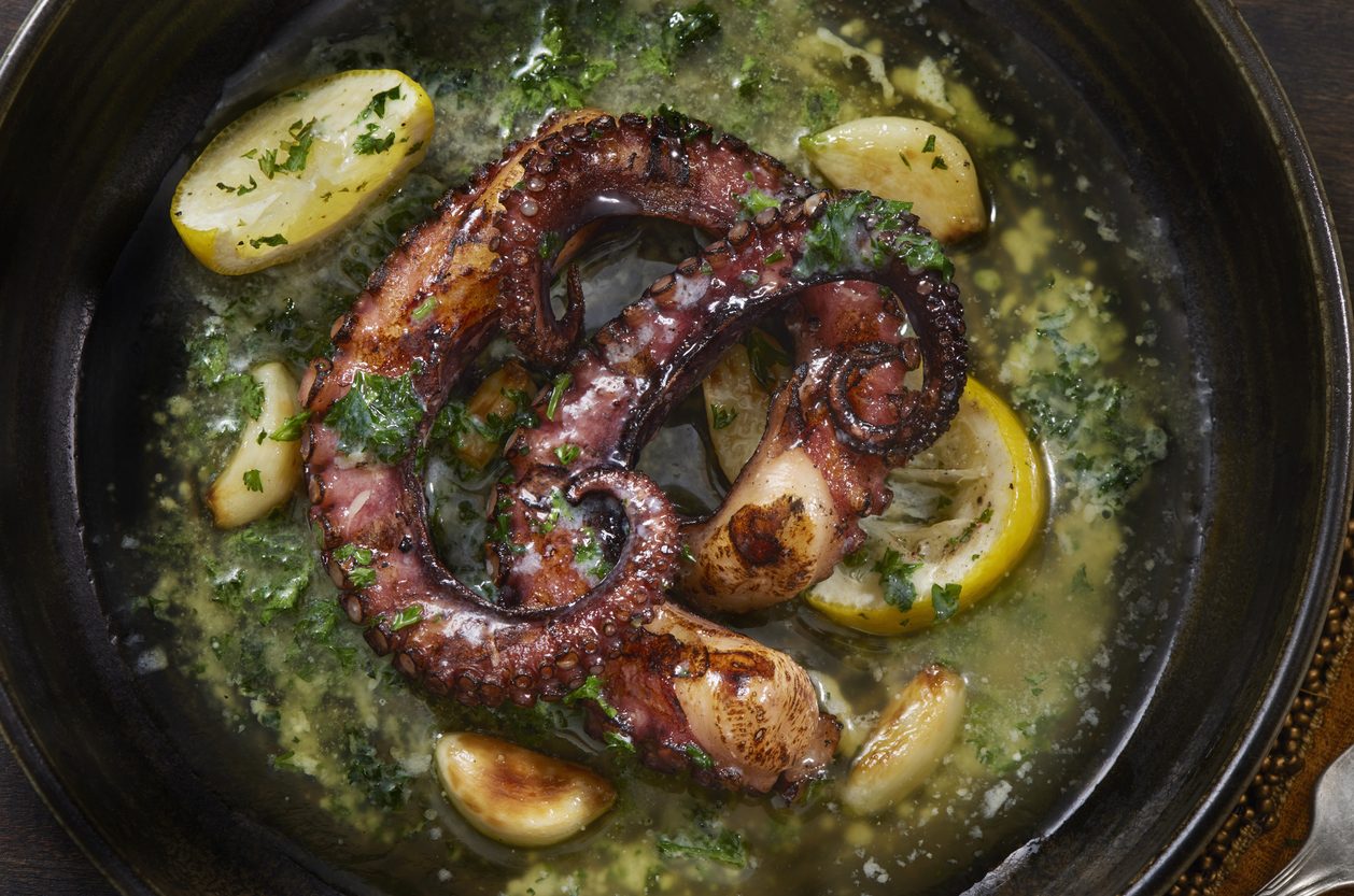Top-down view of octopus tentacles in garlic butter and lemon
