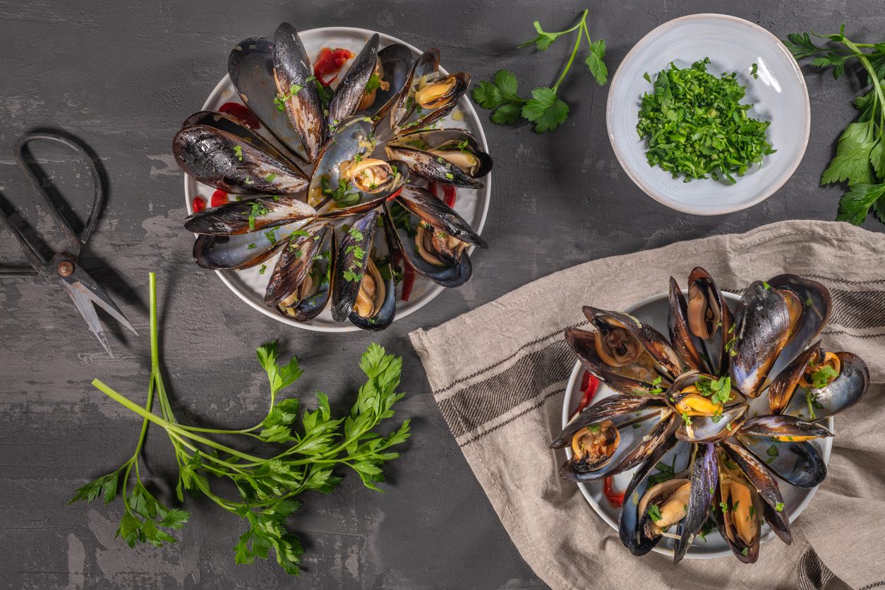 Top view of two plates of mussels and chopped parsley