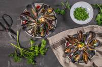 Top view of two plates of mussels and chopped parsley