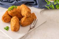 Pile of fritters on a white plate with a fork