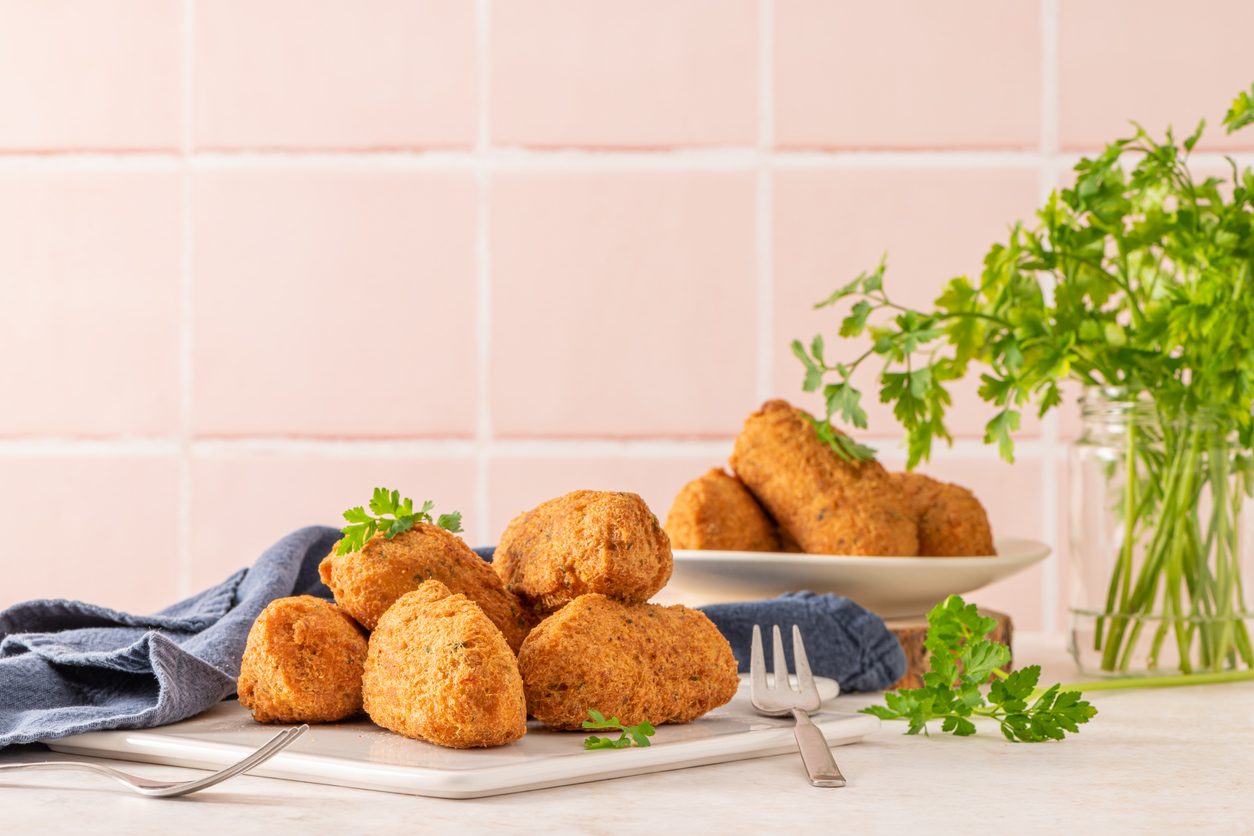 Fritters on a white platter with parsley and forks