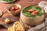 Bowl of soup with chouriço slices and broa bread slices.