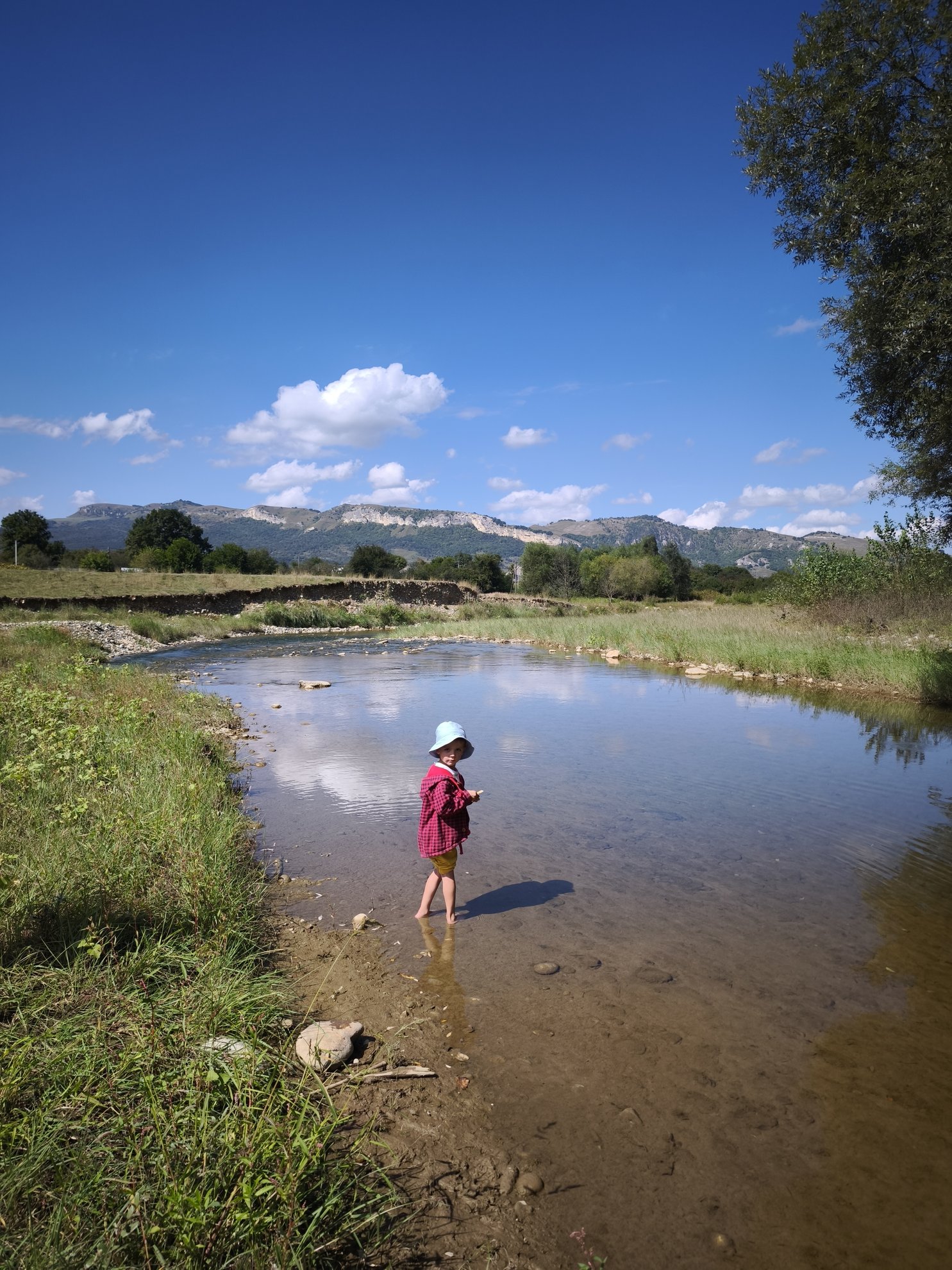 River bank with shallow water and mountains in background