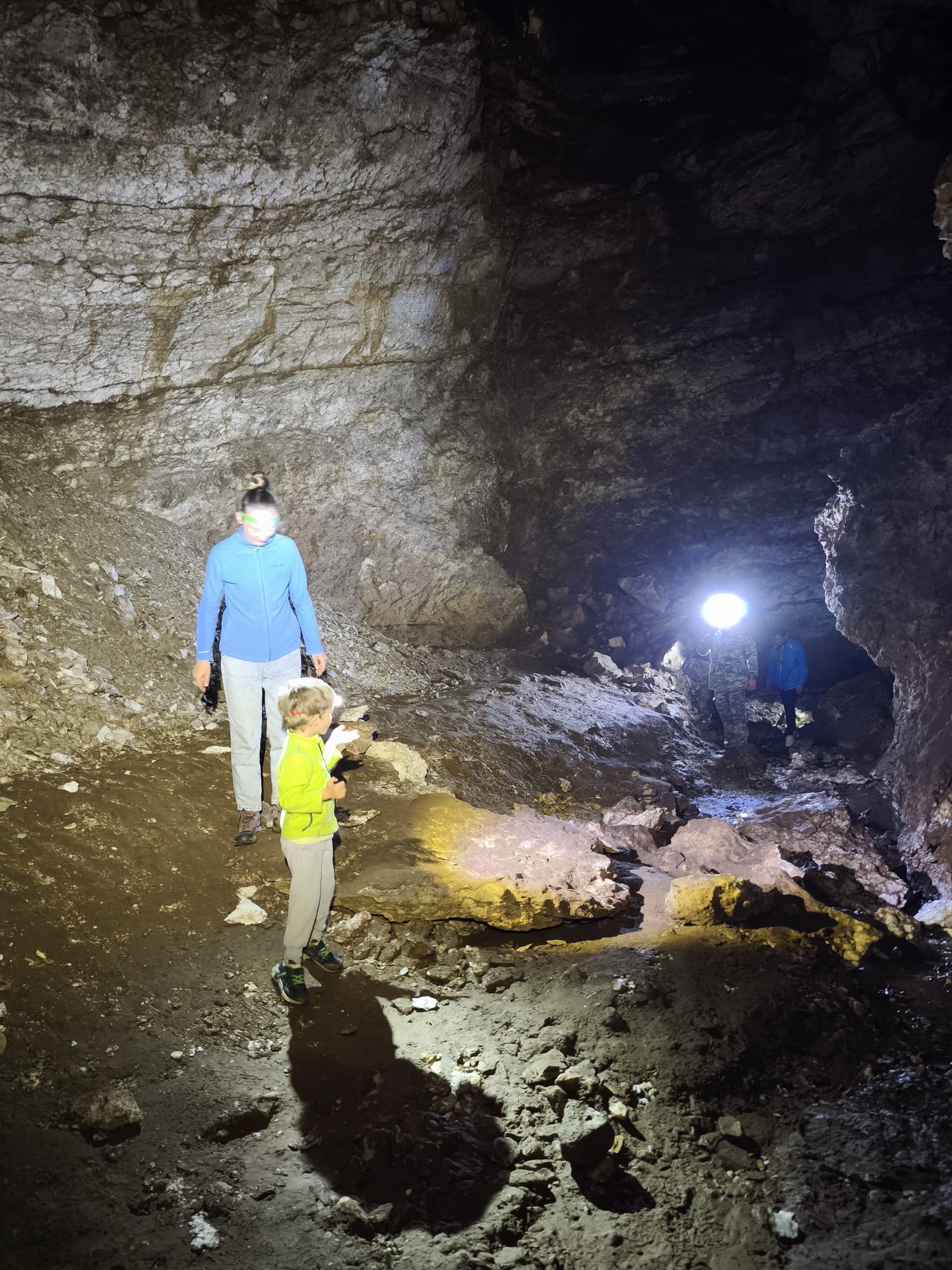 chão rochoso da gruta e paredes de pedra iluminadas por lanternas de cabeça