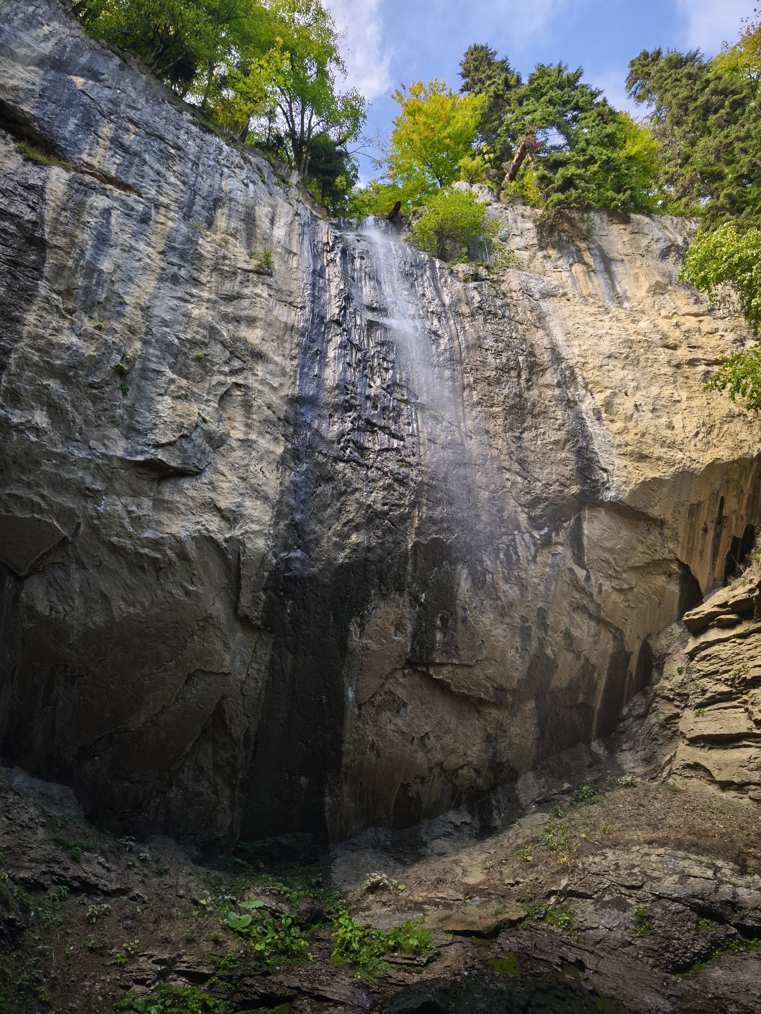 Low angle view of the waterfall falling against rock face