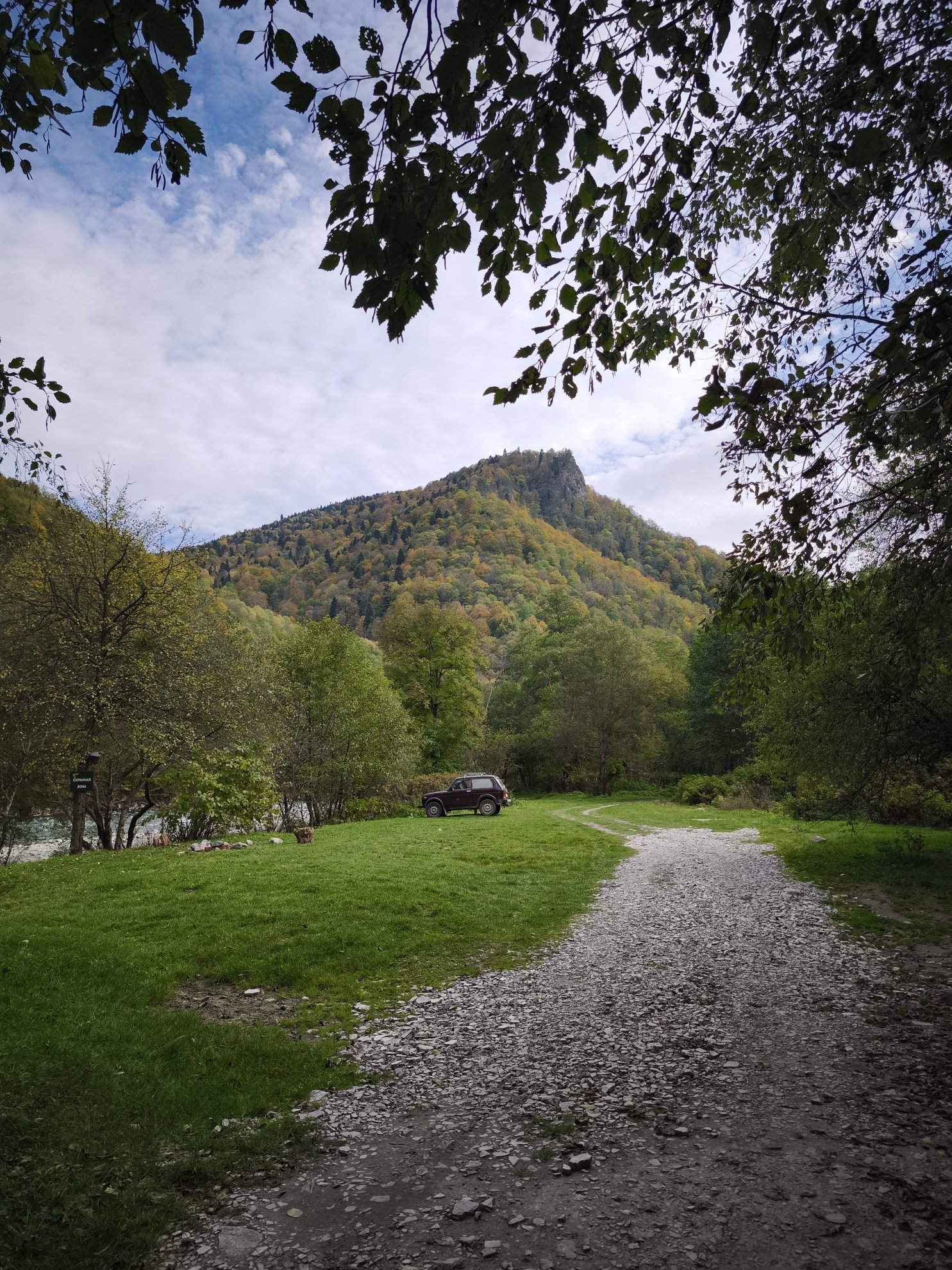 gravel road leading toward a mountain and car